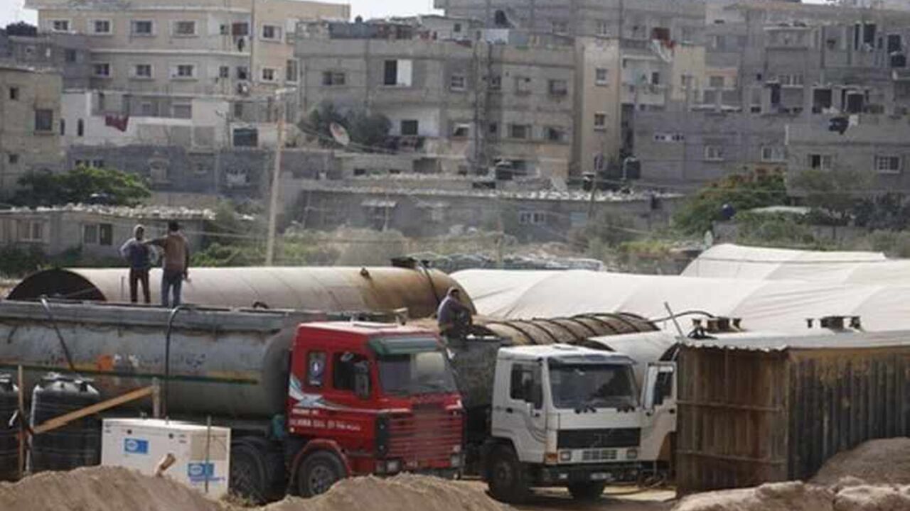 EGYPT-PROTESTS/PIPELINE Palestinians wait as they fill tankers with fuel on the border between Egypt and southern Gaza Strip July 8, 2013. Armed men launched a series of attacks on Sunday on security checkpoints in the North Sinai towns of Sheikh Zuweid and El Arish close to Egypt's border with Israel and the Gaza Strip, and one soldier was killed. The Rafah border crossing between Egypt and Gaza Strip remained closed since Friday. REUTERS/Ibraheem Abu Mustafa (GAZA - Tags: POLITICS CIVIL UNREST MILITARY ENERGY) - RTX11GFQ