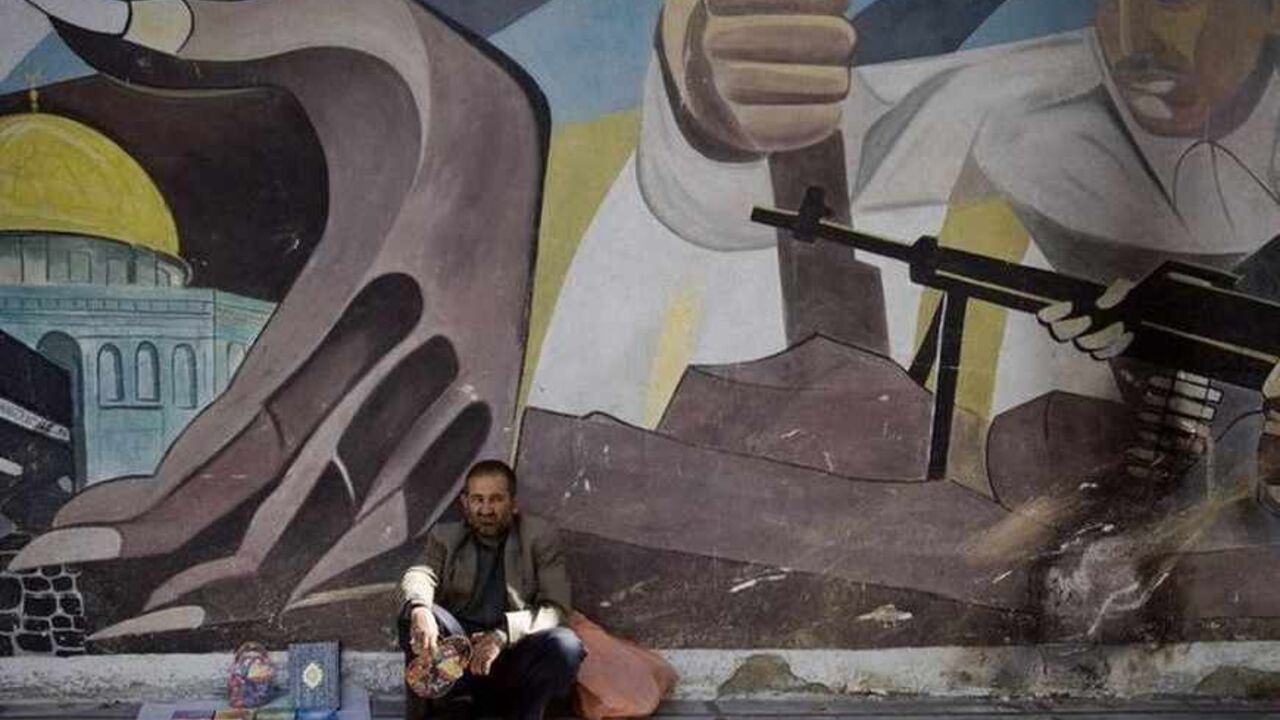 A vendor sits under an anti-Israel mural during a demonstration after Friday prayers in Tehran EDITORS' NOTE: Reuters and other foreign media are subject to Iranian restrictions on their ability to film or take pictures in Tehran.
A vendor sits under an anti-Israel mural during a demonstration after Friday prayers in Tehran October 9, 2009. REUTERS/Morteza Nikoubazl (IRAN POLITICS RELIGION) - RTXPGS2