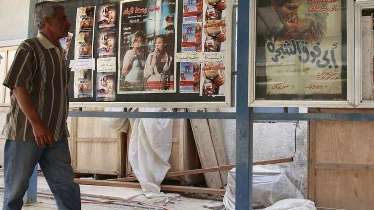 To match Feature IRAQ-CINEMA A resident walks at the entrance of a cinema in Baghdad April 26, 2011. Iraq once had 82 cinemas, 64 of them located in the teeming capital, home to about 7 million of Iraq's 30 million people. One by one, they closed during the Saddam era, when the government controlled the selection and importation of films, until only five remained at the time of the invasion. The insurgency that followed and killed tens of thousands of people made Iraqis afraid of being in public places and crowds. They chose the relati