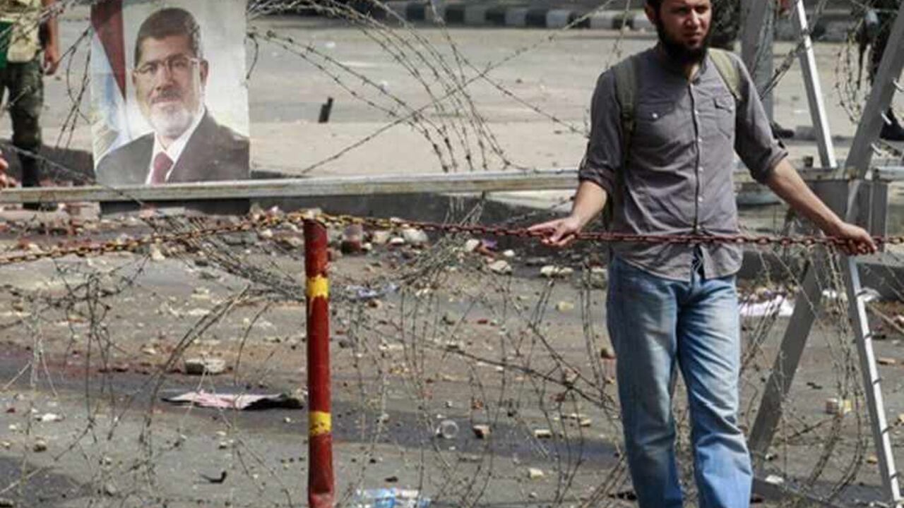 EGYPT-PROTESTS A supporter of deposed Egyptian President Mohamed Mursi stands behind concertina wire outside the Republican Guard headquarters in Cairo July 9, 2013. Egypt's interim President Adli Mansour on Tuesday named liberal economist and former finance minister Hazem el-Beblawi as prime minister in a transitional government, as the authorities sought to steer the country to new parliamentary and presidential elections. REUTERS/Louafi Larbi (EGYPT - Tags: POLITICS CIVIL UNREST) - RTX11I1R