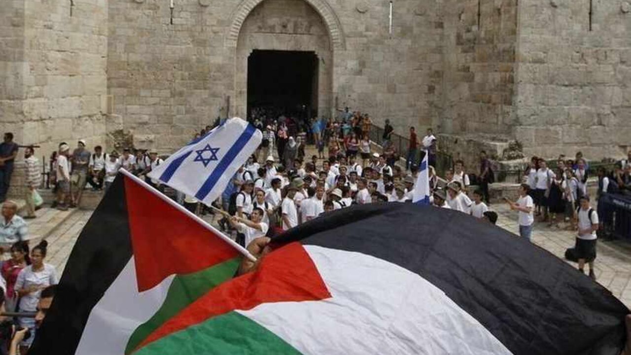 Palestinians wave flags as Israeli youths gather in front of the Damascus Gate in Jerusalem's Old City Palestinians wave Palestinian flags as Israeli youths celebrating Jerusalem Day gather in front of the Damascus Gate in Jerusalem's Old City May 8, 2013. Jerusalem Day marks the anniversary of Israel's capture of the Eastern part of the city during the 1967 Middle East War. In 1980, Israel's parliament passed a law declaring united Jerusalem as the national capital, a move never recognised internationally. REUTERS/Ammar Awad (JERUSALEM - Tags: POLITICS ANNIVERSARY) - RTXZEXA