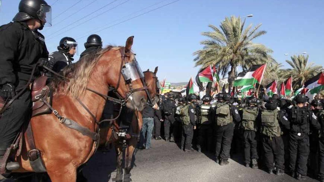 Israeli mounted policemen guard as Israeli-Arab protesters wave Palestinian flags during a demonstration in Umm el-Fahm Israeli mounted policemen guard as Israeli-Arab protesters wave Palestinian flags during a demonstration to show their solidarity with Bedouin citizens, in the Israeli-Arab town of Umm el-Fahm August 1, 2013. Hundreds demonstrated on Thursday against an Israeli cabinet plan to relocate some 30,000 Bedouin citizens who live in unrecognized villages in Israel's southern Negev desert and relocate them to towns built by the government. Clashes erupted at the demonstration as police prevented the protesters from