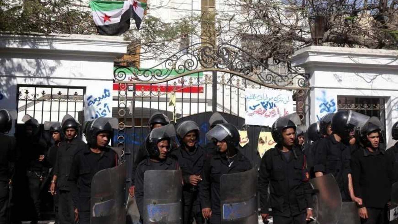 EGYPT-IRAN/ Police stand guard outside the Iranian ambassador's house during a protest against Iran in Cairo April 5, 2013. Ultra-Conservative Islamist Salafists brought down the Iranian flag at the house of the Iranian ambassador in Egypt Mojtaba Amani on Friday, and replaced it with the Syrian revolutionary flag. Seen at the top of the fence is the Syrian revolutionary flag. REUTERS/Mohamed Abd El Ghany (EGYPT - Tags: POLITICS CIVIL UNREST) - RTXY9NK
