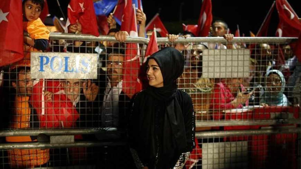 Supporter of Turkish Prime Minister Erdogan stands in front of a police fence as she waits for his arrival at Istanbul's Ataturk airport A supporter of Turkish Prime Minister Tayyip Erdogan stands in front of a police fence as she waits for his arrival at Istanbul's Ataturk airport early June 7, 2013. Erdogan told thousands of cheering supporters on Friday his authority came from the ballot box and urged them not to be drawn into violence, in a show of ruling party strength after a week of fierce anti-government protests. Addressing crowds at Istanbul airport from an open-top bus after returning from a trip to North Africa, Erdogan called on