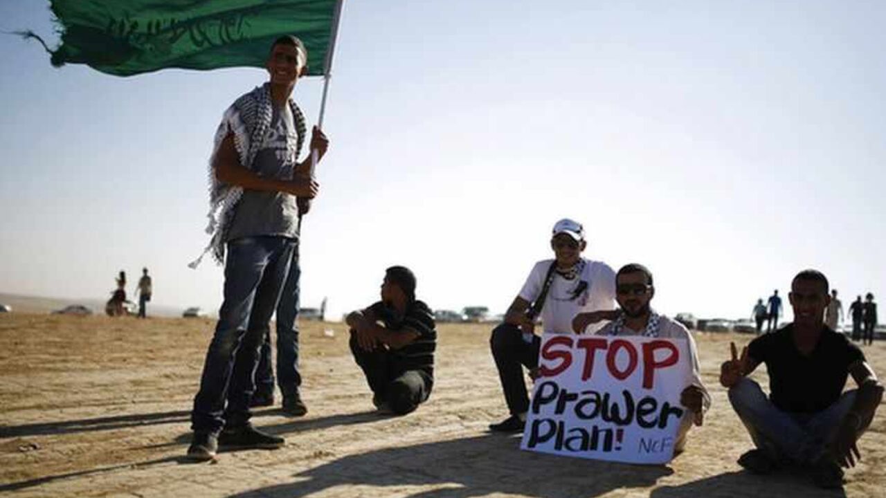 A protester holds a placard as another holds an Islamic movement flag during a demonstration near Rahat A protester holds a placard as another holds an Islamic movement flag during a demonstration to show their solidarity with Bedouin citizens, near the Bedouin town of Rahat in southern Israel August 1, 2013. Hundreds demonstrated against an Israeli cabinet plan to relocate some 30,000 Bedouin citizens who live in unrecognized villages in Israel's southern Negev desert and relocate them to towns built by the government. REUTERS/Amir Cohen (ISRAEL - Tags: POLITICS CIVIL UNREST) - RTX127DJ