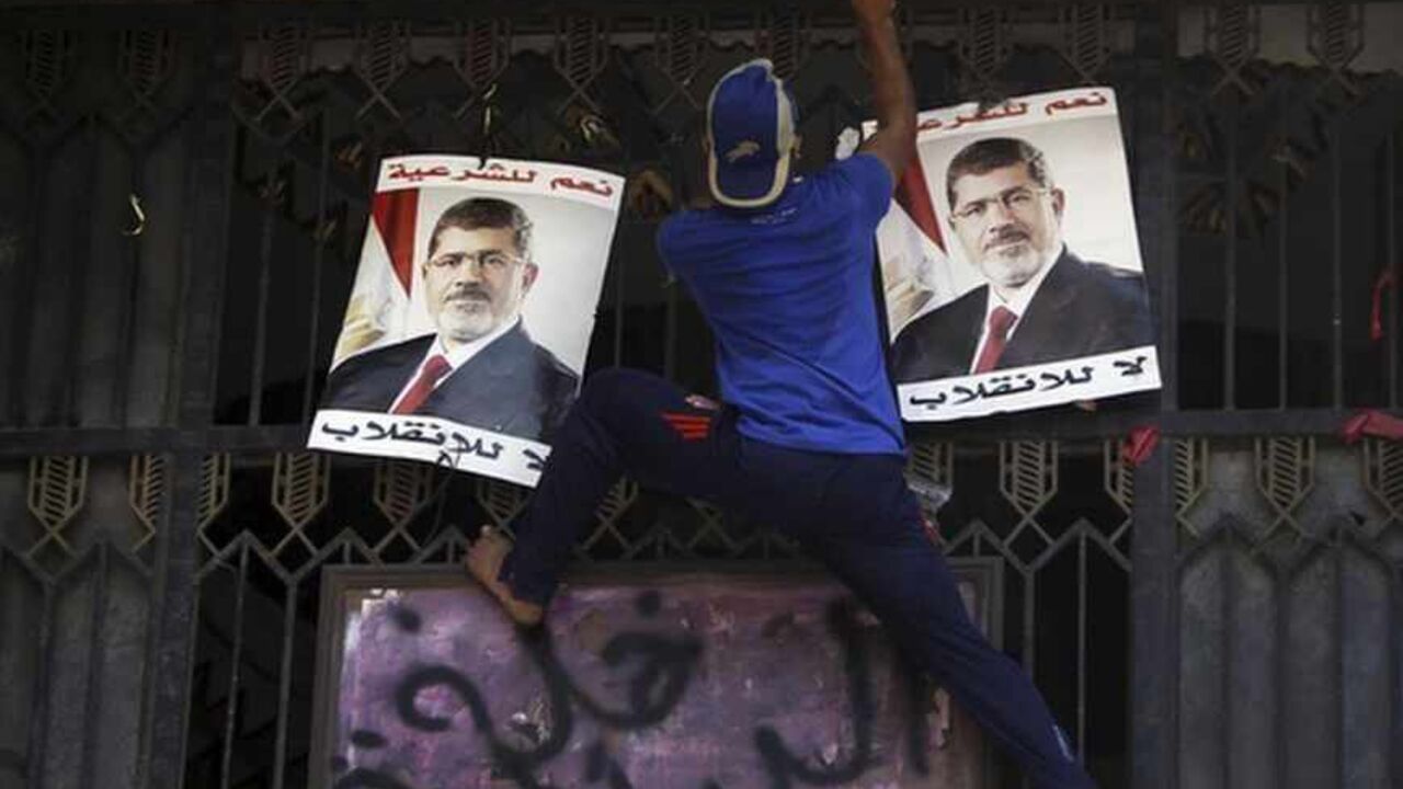 A member of the Muslim Brotherhood and supporter of deposed Egyptian President Mursi climbs up the main door of the Attorney General's office to spray a graffiti during a protest at the courthouse in Cairo A member of the Muslim Brotherhood and supporter of deposed Egyptian President Mohamed Mursi climbs up the main door of the Attorney General's office to spray a graffiti, which reads "Interior thugs", above posters of Mursi during a protest at the courthouse in downtown Cairo August 5, 2013. Several thousand Islamist supporters of Mursi marched through downtown Cairo on Monday calling for his reinstatement and denouncing the army general who led his overthrow. REUTERS/Amr Abdallah Dalsh (EGYPT - Tags: POLIT