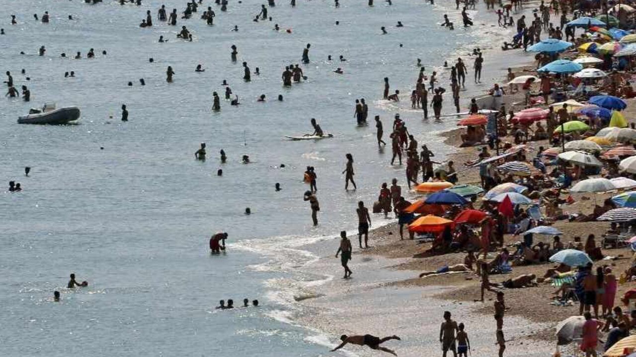 Tourists enjoy the hot weather at Vari beach, some 30 km (19 miles) southeast of Athens July 21, 2013. Foreign tourists are returning to Greece's sun-drenched islands and ancient temples, central bank data showed on Friday, boosting hopes that the key sector may help the crisis-hit country pull itself out of a severe economic recession.    REUTERS/Yannis Behrakis (GREECE - Tags: ENVIRONMENT BUSINESS TRAVEL SOCIETY) - RTX11TYN