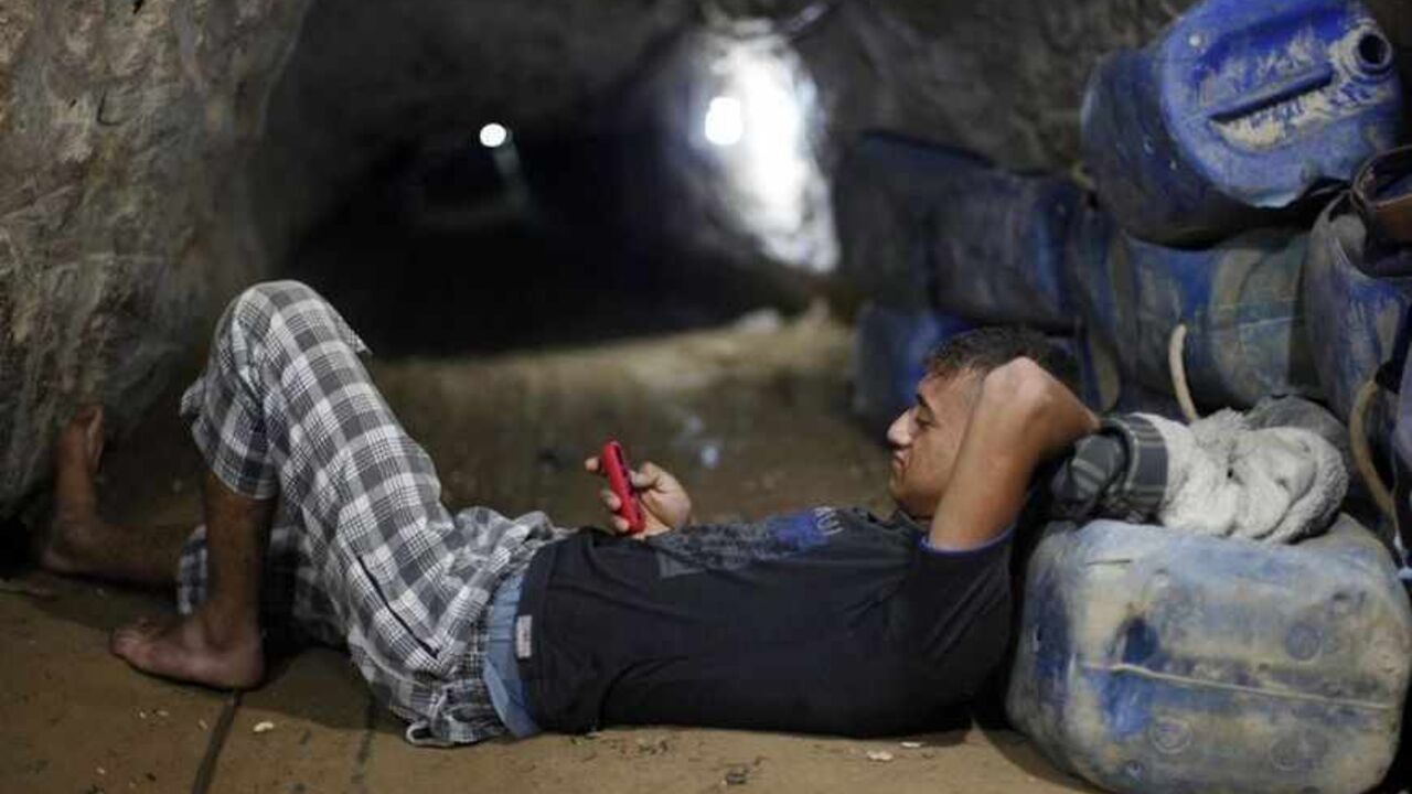 Palestinian tunnel worker uses his mobile as he rests inside a smuggling tunnel beneath the Gaza-Egypt border in the southern Gaza Strip A Palestinian tunnel worker uses his mobile as he rests inside a smuggling tunnel beneath the Gaza-Egypt border in the southern Gaza Strip July 19, 2013. The Islamist group Hamas appealed to Egypt's new rulers on Thursday not to pursue its destruction of smuggling tunnels into the Gaza Strip, warning they risked throttling the small Palestinian territory. REUTERS/Ibraheem Abu Mustafa (GAZA - Tags: POLITICS TPX IMAGES OF THE DAY) - RTX11ROK