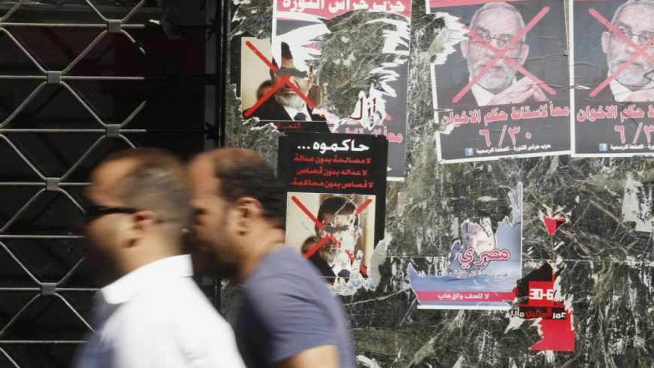 People walk in front of defected posters of ousted Egyptian President Mursi and Muslim Brotherhood leader Badie in downtown Cairo People walk in front of defected posters of ousted Egyptian President Mohamed Mursi and Muslim Brotherhood leader Mohammed Badie in downtown Cairo August 29, 2013. After a stunning reversal in which the army seized upon a tide of public discontent to overthrow freely elected President Mohamed Mursi, the powerful state apparatus appears to have all but neutralised the Muslim Brotherhood to which he belongs. Poster (R) reads, "To be on trial... No reconciliation without justice, no justice without retribution