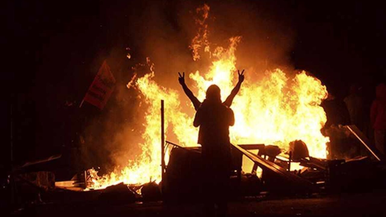 TURKEY-PROTESTS/ALEVIS A demonstrator gestures as he stands behind burning barricades during a protest in the Tuzlucayir neighbourhood of Ankara September 9, 2013. Billed as a symbol of peace between two faiths, a new place of worship has turned Tuzlucayir, a poor suburb of Ankara, into a battleground and exposed wider sectarian tensions within Turkey. The project's blueprint envisages a Sunni mosque rising side by side with a new cemevi, or assembly house, to be used by Alevis, Turkey's biggest religious minority. But with its c