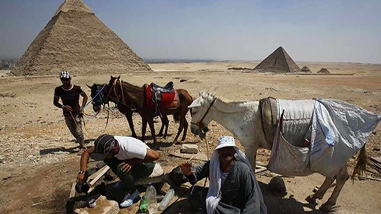 EGYPT-TOURISM/ Camel guides drink tea as they wait for customers at the Pyramids Plateau in Giza Pyramids, on the outskirts of Cairo August 26, 2013. REUTERS/Youssef Boudlal (EGYPT - Tags: SOCIETY TRAVEL ANIMALS) - RTX12XEU