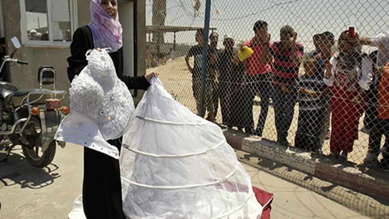 PALESTINIANS/ Palestinian Doa'a Abu Mosabeh holds her wedding dress as she tries to cross into Egypt at Rafah border crossing in the southern Gaza Strip June 21, 2011. Abu Mosabeh's wedding is set for Thursday June 23 in Qatar and she has been unable to leave Gaza Strip due to the slow passage movement at Rafah border crossing with Egypt. REUTERS/Ibraheem Abu Mustafa (GAZA - Tags: POLITICS) - RTR2NWY7