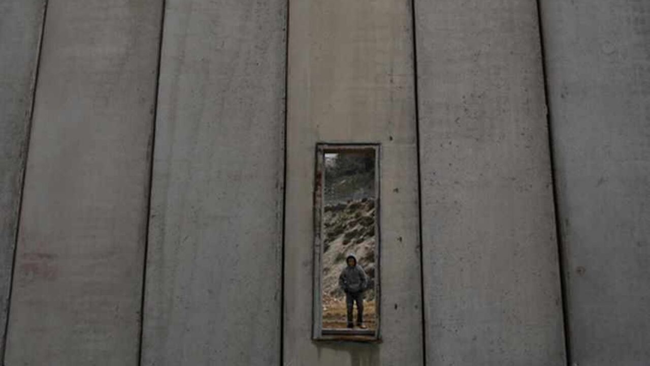 Palestinian boy is seen through opening in barrier in Shuafat A Palestinian boy is seen through an opening in Israel's controversial barrier in Shuafat in the West Bank near Jerusalem February 17, 2009. REUTERS/Baz Ratner (WEST BANK) - RTXBQ43