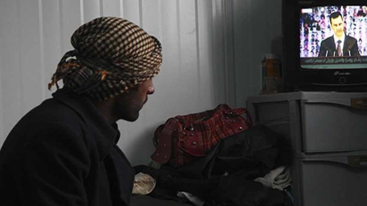 SYRIA-CRISIS/ASSAD A Syrian refugee watches a television broadcast of Syria's President Bashar al-Assad speaking in Damascus, in their container at the Al-Zaatari refugee camp in the Jordanian city of Mafraq, near the border with Syria, January 6, 2013. Assad made his first public appearance in months on Sunday, calling for a "full national mobilisation" to fight against rebels he described as al Qaeda terrorists. REUTERS/Majed Jaber (JORDAN - Tags: POLITICS CIVIL UNREST) - RTR3C5EE
