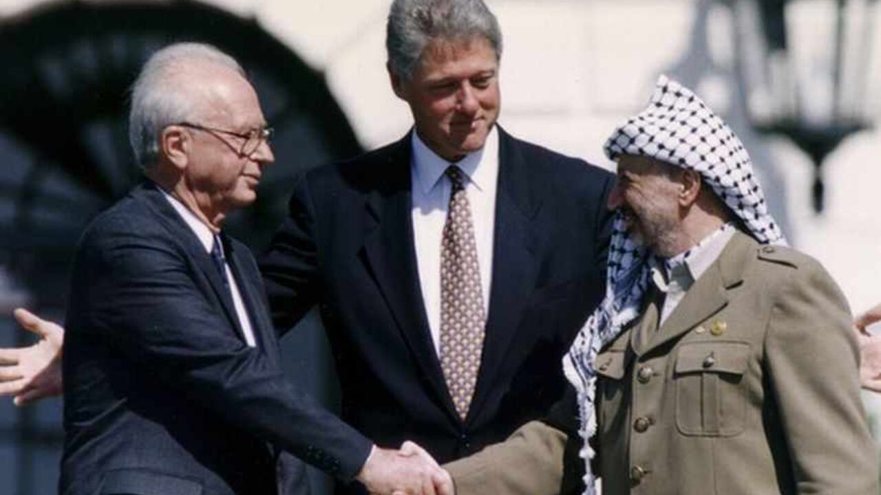 PLO Chairman Arafat shakes hands with Israeli PM Rabin after the signing of the Israeli-PLO peace accord, in Washington PLO Chairman Yasser Arafat (R) shake hands with Israeli Prime Minister Yitzhak Rabin (L), as U.S. President Bill Clinton stands between them, after the signing of the Israeli-PLO peace accord, at the White House in Washington September 13, 1993. REUTERS/Gary Hershorn (UNITED STATES - Tags: POLITICS) - RTX13K52