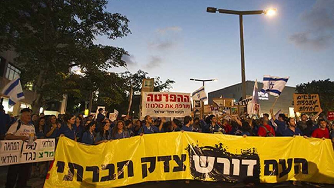 ISRAEL/ Protesters hold a placard in Hebrew reading, "the People demand social justice" during a demonstration calling for social justice in Tel Aviv June 30, 2012. REUTERS/Nir Elias (ISRAEL - Tags: POLITICS CIVIL UNREST SOCIETY) - RTR34F92
