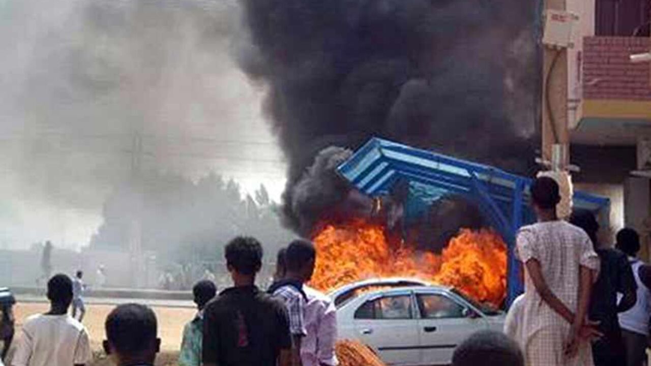 SUDAN-PROTEST/ People look at burning cars during protests over fuel subsidy cuts in Khartoum September 25, 2013. At least 27 people have been killed in protests in Khartoum over fuel subsidy cuts, a medical source said on Thursday as another bout of the worst unrest seen in Sudan's relatively well-off central regions for years broke out in its biggest port. Thousands had marched in Khartoum on Wednesday, torching cars, buildings and petrol stations. Picture taken September 25, 2013. REUTERS/Stringer (SUDAN - Tags: CIVIL