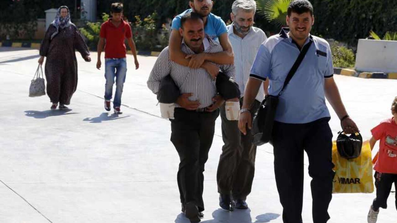SYRIA-CRISIS/TURKEY Mustafa Abu Bekir, 23, is carried by a family member as they enter Turkey from the Turkish Cilvegozu border gate, located opposite the Syrian commercial crossing point Bab al-Hawa, in Reyhanli, Hatay province, September 9, 2013. Abu Bekir introduced himself as a Free Syrian Army fighter who was severely injured and lost his legs during a bombing by the Syrian Air Force while he and others were fighting in the front line against forces loyal to Syria's President Bashar al-Assad in Iblib almost a month ago. T