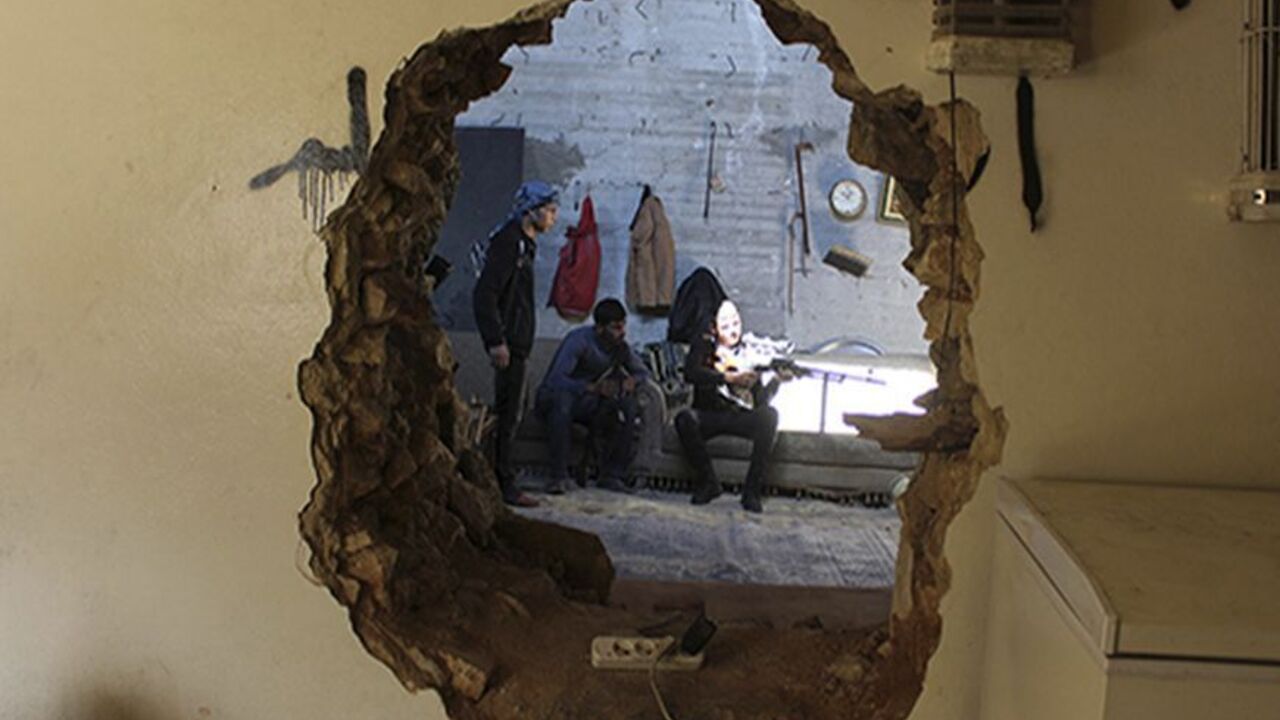 SYRIA-CRISIS/ A Free Syrian Army fighter aims his weapon as he is seen through a hole in a wall in Aleppo's Karm al-Jabal district October 21, 2013. REUTERS/Molhem Barakat (SYRIA - Tags: POLITICS CIVIL UNREST CONFLICT) - RTX14IU3