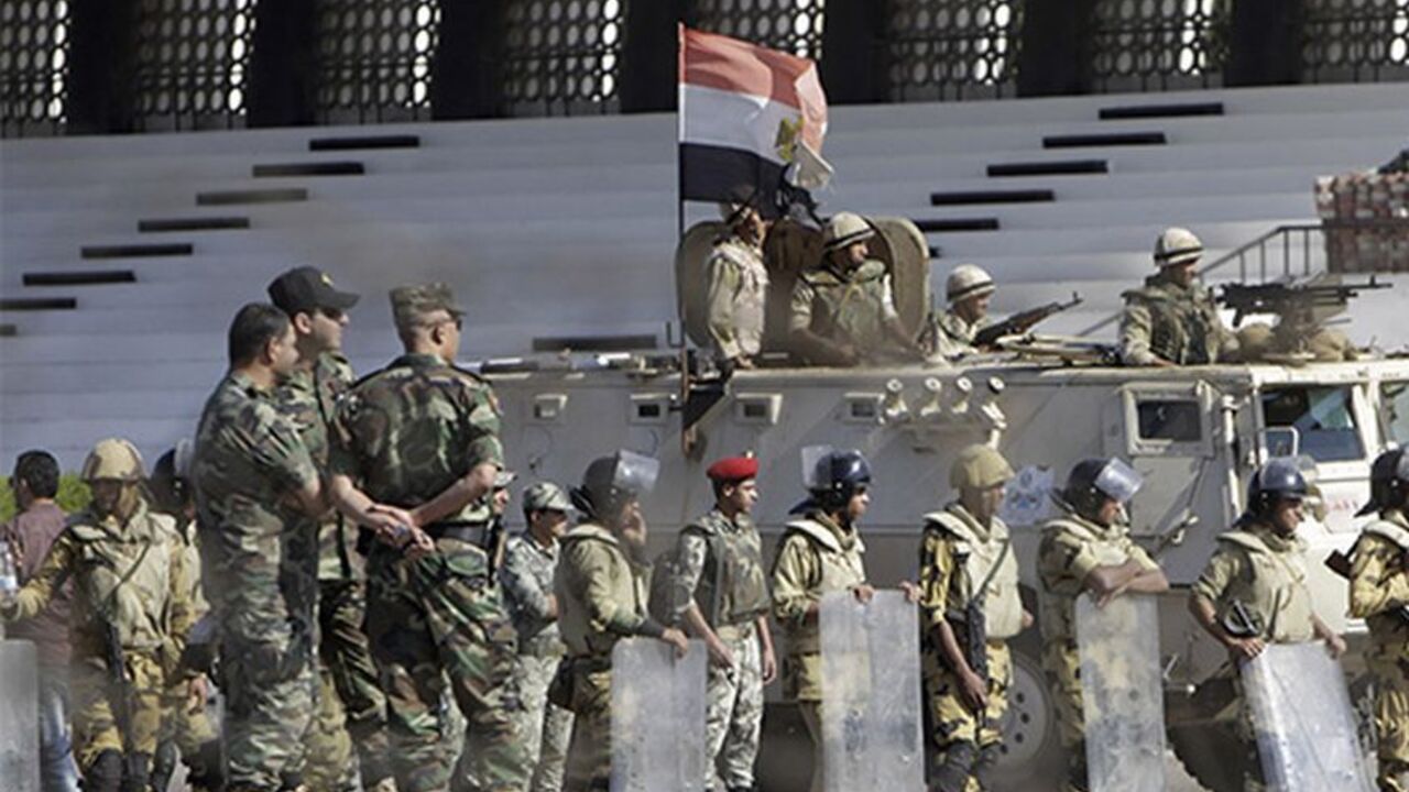 EGYPT-PROTESTS/ Military personnel stand next to an armoured personnel carrier during a protest near Al-Azhar University in Cairo October 20, 2013. Egyptian security forces fired bird shot and tear gas to prevent supporters of deposed Islamist President Mohamed Mursi from marching on Sunday to the site of a protest camp at Rabaa al-Adaweya mosque that was destroyed two months ago, a Reuters witness said. The crowd of about 500 people were students from Al-Azhar University. REUTERS/Mohamed Abd El Ghany (EGYPT - Tags: POLIT