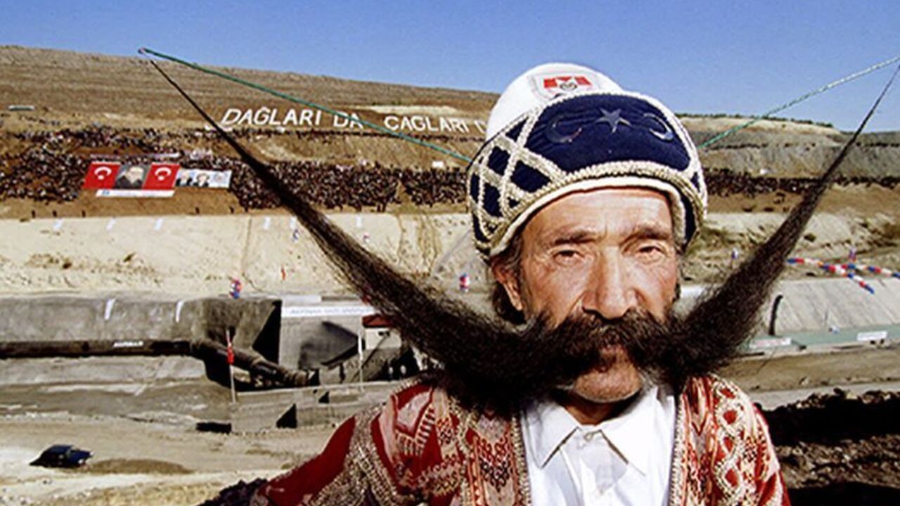 TURKEY 50-year-old Mevlut Dogan of Turkey poses with his 1,5 metres long moustache in front of the irrigation tunnel in the southeast Turkish town of Sanliurfa November 9. He was one of the characters present during the inauguration of the next stage of Turkey's regional development project by opening up the world's largest irrigation tunnel for a ceremonial run - RTXF4TZ