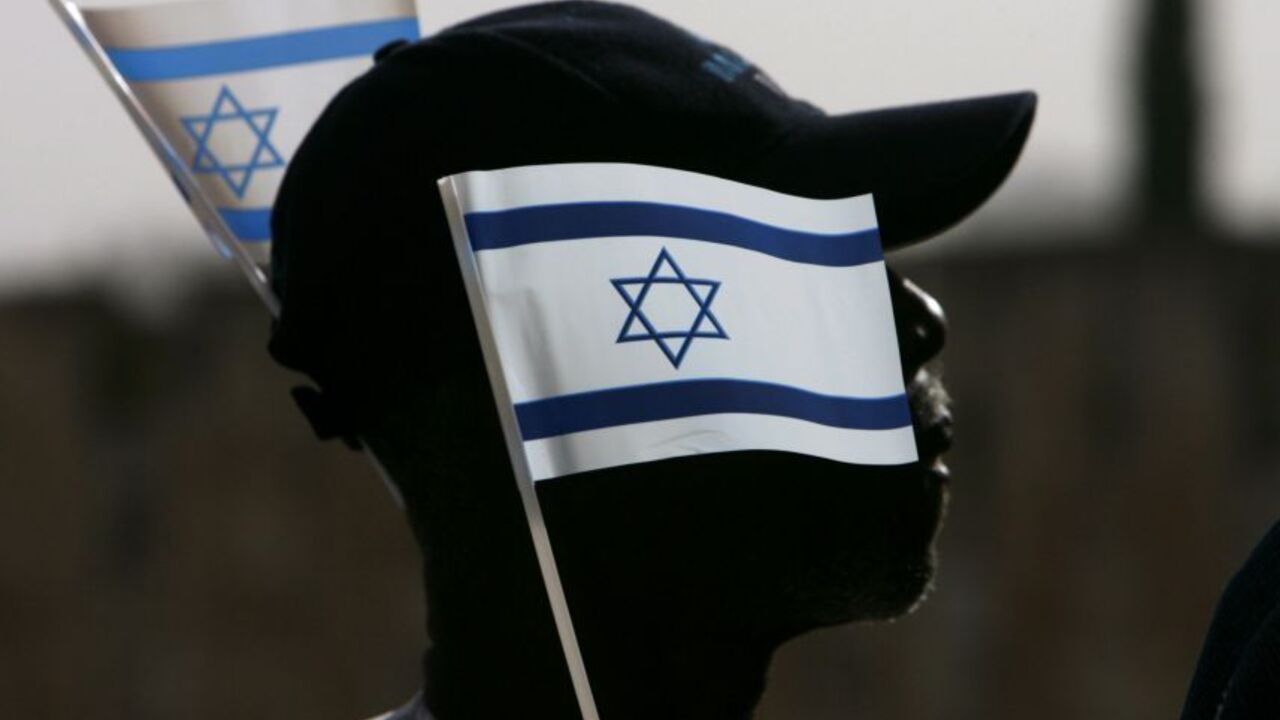 A Nigerian pilgrim holds Israel's national flag during a gathering in the Old City of Jerusalem March 18, 2008. According to Israel's Ministry of Tourism, some 1,000 tourists from Nigeria took part in a gathering to kick off Israel's 60th anniversary celebrations. REUTERS/Ronen Zvulun (JERUSALEM) - RTR1YH1M