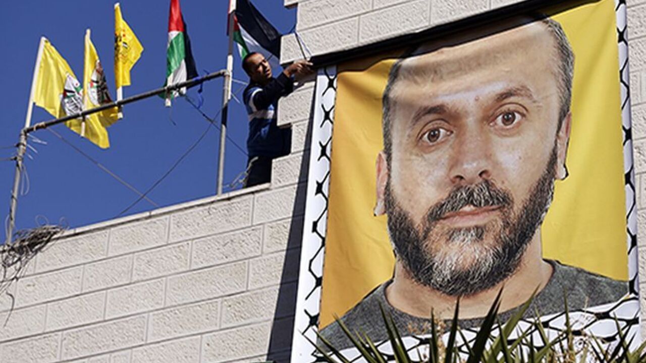 PALESTINIANS/ A relative hangs a banner depicting Palestinian prisoner Moses Qar'an outside his house, in the West Bank city of Ramallah October 28, 2013. Israel is to release 26 Palestinian prisoners in the second stage of a deal brokered by the U.S. in July that brought about the resumption of peace talks. REUTERS/Mohamad Torokman (WEST BANK - Tags: CIVIL UNREST POLITICS) - RTX14R4A