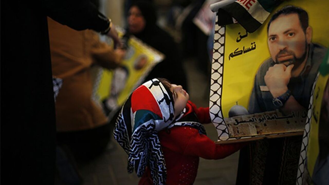 PALESTINIANS-ISRAEL/ A Palestinian girl looks at a picture of a jailed relative during a protest demanding the release of all Palestinian prisoners held in Israeli jails, in Gaza City October 28, 2013. Israel is to release 26 Palestinian prisoners in the second stage of a deal brokered by the U.S. in July that brought about the resumption of peace talks. The words on top of the poster read, "We will not forget you". REUTERS/Suhaib Salem (GAZA - Tags: POLITICS CIVIL UNREST CONFLICT TPX IMAGES OF THE DAY) - RTX14R3N