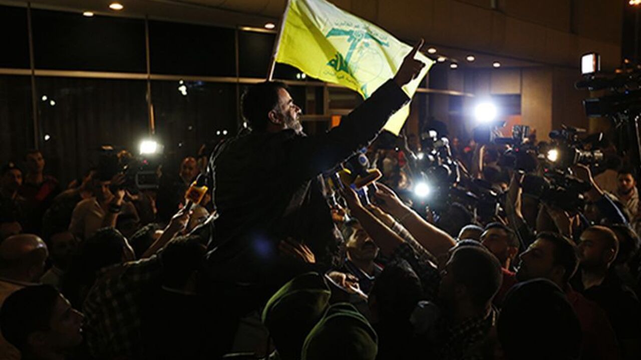 SYRIA-CRISIS/HOSTAGES One of the nine newly released Lebanese hostages, who were held by rebels in northern Syria, carries a Hezbollah flag as he is welcomed by his relatives upon his arrival at Beirut international airport, October 19, 2013. A plane with nine Lebanese hostages freed from northern Syria landed safely in Beirut on Saturday night, witnesses said, nearly a year and a half after the men were captured by Syrian rebels near the Turkish border. REUTERS/Mohamed Azakir (LEBANON - Tags: POLITICS CIVIL UNREST) - RTX14H60