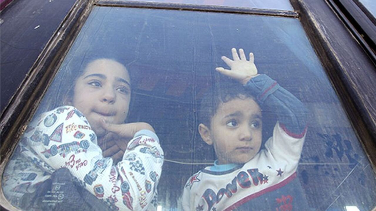 PALESTINIANS-EGYPT/GAZA Palestinian children hoping to cross into Egypt, look out of a bus window at the Rafah crossing between Egypt and the southern Gaza Strip October 8, 2013. Egypt partially reopened its border crossing with the Gaza Strip for four days on Tuesday for the humanitarian needs of patients seeking treatment, and students studying outside of Gaza, a Palestinian official said. REUTERS/Ahmed Zakot (GAZA - Tags: POLITICS TPX IMAGES OF THE DAY SOCIETY IMMIGRATION) - RTX143OA