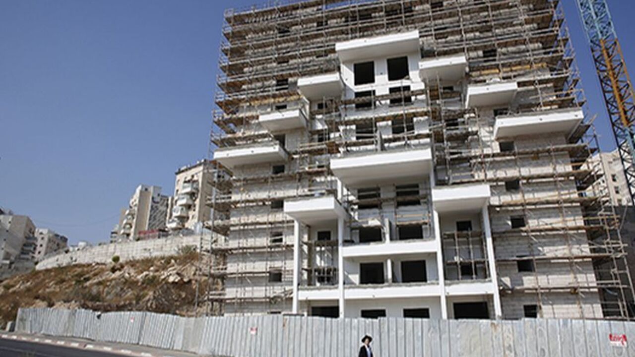 PALESTINIANS-ISRAEL/SETTLEMENT An ultra-Orthodox youth walks past a construction site in the West Bank Jewish settlement of Modiin Illit October 17, 2013. Housing starts in Jewish settlements in the occupied West Bank are up by 70 percent this year, the anti-settlement Peace Now group said on Thursday, despite reports Israel has been quietly delaying new construction. REUTERS/Baz Ratner (WEST BANK - Tags: BUSINESS CONSTRUCTION POLITICS TPX IMAGES OF THE DAY) - RTX14EUM
