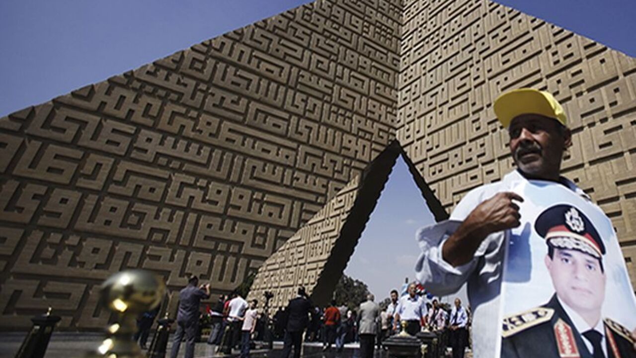 EGYPT-PROTESTS/ A man holds a poster Army Chief General Abdel Fattah al-Sisi at the tomb of late Egyptian President Anwar Sadat, during the 40th anniversary of Egypt's attack on Israeli forces during the 1973 war, at Cairo's Nasr City district, October 6, 2013. REUTERS/Amr Abdallah Dalsh (EGYPT - Tags: POLITICS CIVIL UNREST MILITARY ANNIVERSARY) - RTR3FNLW