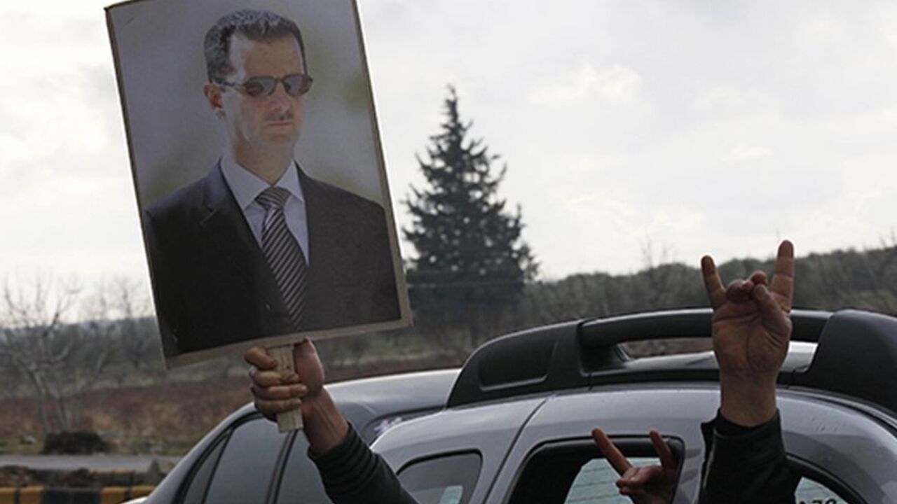 TURKEY-SYRIA/ Turkish men flash nationalist gestures while carrying a poster of Syria's President Bashar al-Assad as they drive to the Oncupinar border crossing during a demonstration in support of Syrian government near the Turkish-Syrian border town of Kilis, Gaziantep province, January 12, 2012. REUTERS/Umit Bektas (TURKEY - Tags: POLITICS CIVIL UNREST) - RTR2W6OM