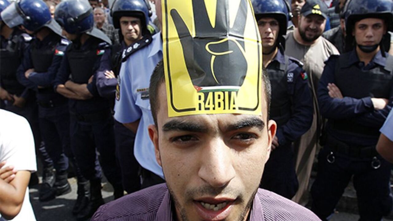 JORDAN/ A supporter of Jordan's opposition parties wearing a sign on his forehead shouts slogans demanding freedom for political prisoners, political and economic reforms, and access to government corruption cases during a demonstration after Friday prayers in Amman October 4, 2013. Anti-government protesters across the region have been using the four-fingered salute on a yellow background, which represents those who were killed in Cairo's al-Rabia Square in Egypt in August, as a tacit statement of opposition to th