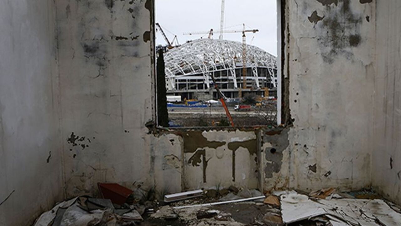 OLYMPICS/ A picture shot through the window of a house that has to be torn down as it is within the perimeters of the Olympic Park shows the Olympic stadium for the Sochi 2014 Winter Olympics at the Olympic Park in Adler, near Sochi February 18, 2013. Although many complexes and venues in the Black Sea resort of Sochi mostly resemble building sites that are still under construction, there is nothing to suggest any concern over readiness. Construction will be completed by August 2013 according to organizers. The Sochi