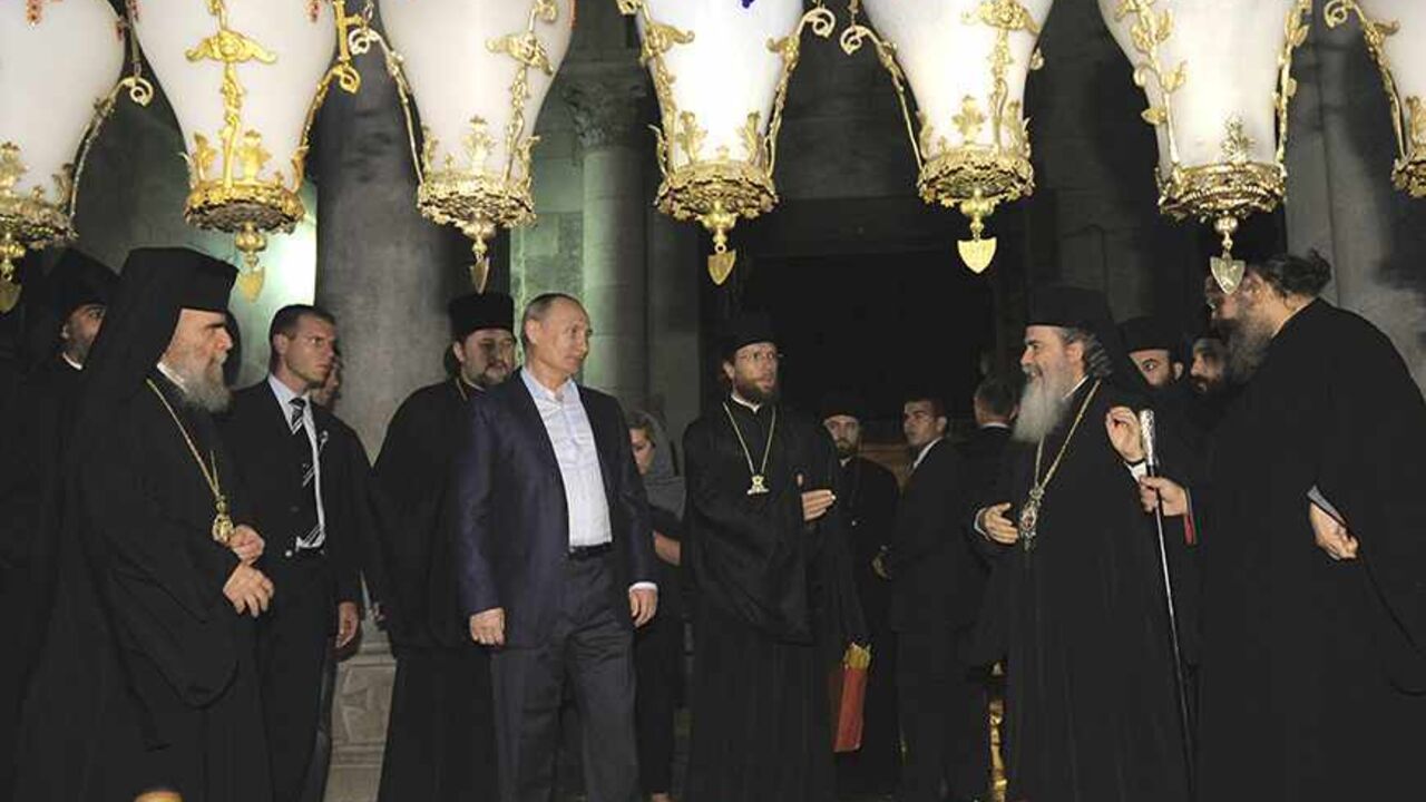 JERUSALEM/ Russia's President Vladimir Putin (5th L) and Greek Orthodox Patriarch of Jerusalem Metropolitan Theophilos (front 2nd R) stand near the Stone of Anointing, where Christians believe the body of Jesus was prepared for burial, at the Church of the Holy Sepulchre in Jerusalem's Old City June 26, 2012. REUTERS/Alexsey Druginyn/RIA Novosti/Pool (JERUSALEM - Tags: POLITICS RELIGION) THIS IMAGE HAS BEEN SUPPLIED BY A THIRD PARTY. IT IS DISTRIBUTED, EXACTLY AS RECEIVED BY REUTERS, AS A SERVICE TO CLIENTS - RTR345VK