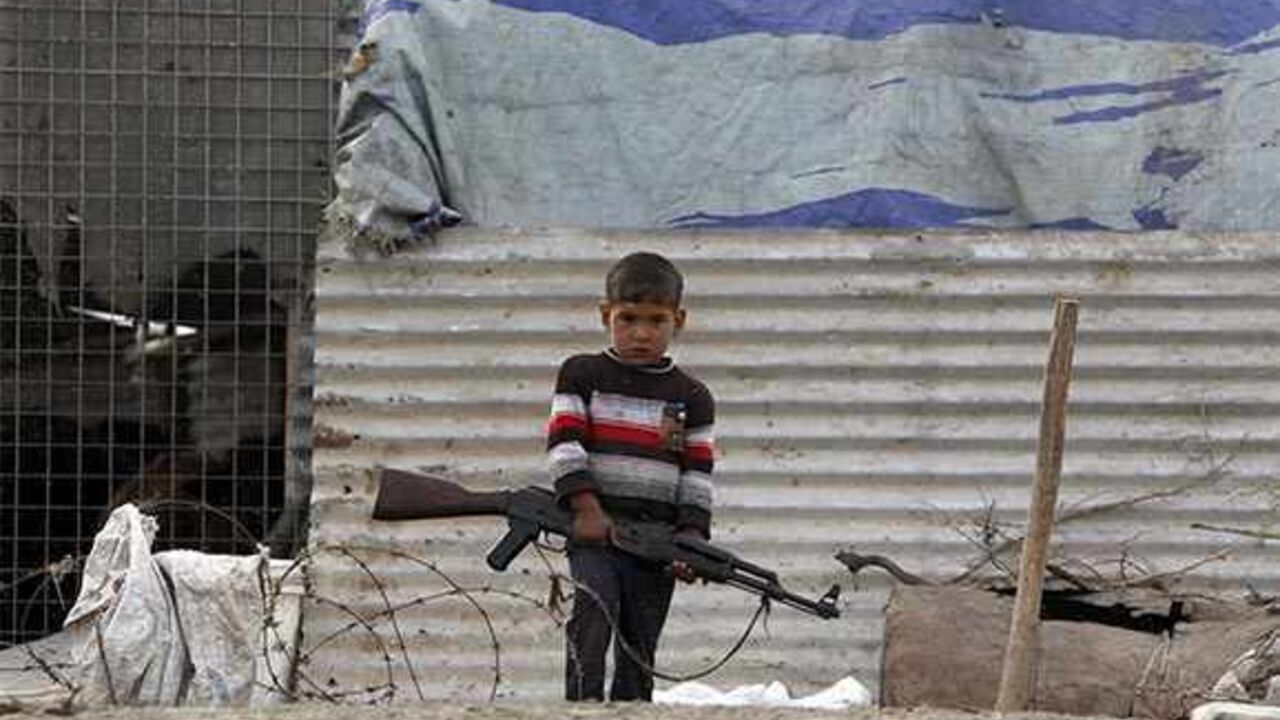 A boy carries a AK47 rifle at the Chebayesh marsh in Nassiriya, 300 km (185 miles) southeast of Baghdad, February 15, 2013. The Marsh Arabs who had farmed this area for thousands of years, were badly affected by a campaign mounted by the government of Saddam Hussein in the 1990s to destroy their lifestyle. The marshes were drained of water, and hundreds of thousands of Marsh Arabs were forced to flee to cities, where they live in poverty, the locals in this area said. Picture taken February 15.    REUTERS/T
