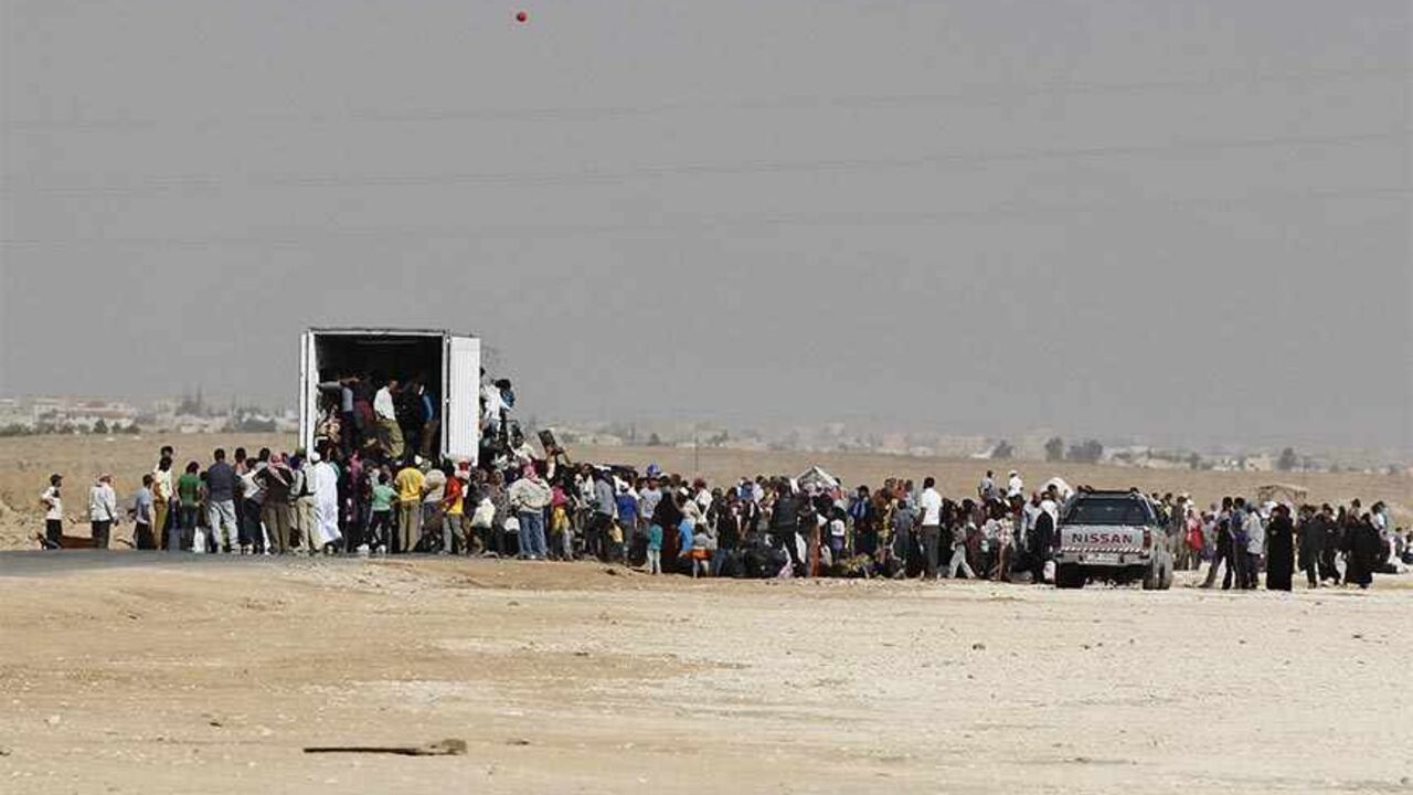 SYRIA-CRISIS/ Syrians refugees try to enter a truck which will transport them back to their homeland at the Al-Zaatri refugee camp in the Jordanian city of Mafraq, near the border with Syria July 30, 2013. REUTERS/Muhammad Hamed (JORDAN - Tags: POLITICS CIVIL UNREST SOCIETY IMMIGRATION) - RTX1258L