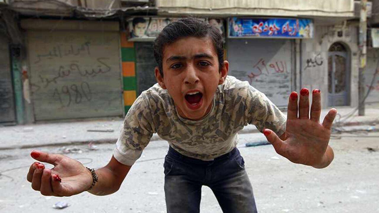 SYRIA-CRISIS/ A boy gestures at the camera with blood on his fingers after what activists said was shelling by forces loyal to Syria's President Bashar al-Assad in the al-Myassar neighbourhood of Aleppo September 19, 2013. REUTERS/Hamid Khatib (SYRIA - Tags: CONFLICT CIVIL UNREST TPX IMAGES OF THE DAY) - RTX13R1I