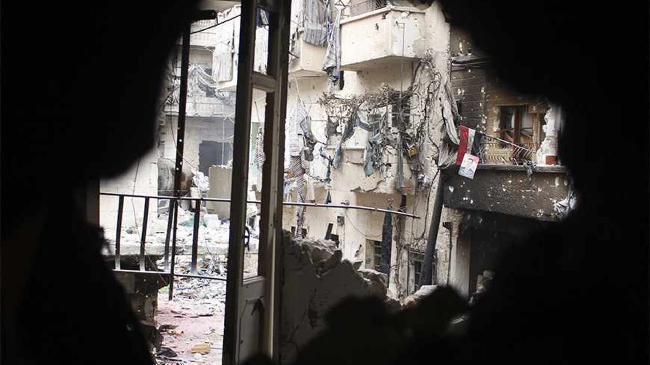 SYRIA-CRISIS/ A picture of Syria's President Bashar al-Assad and a Syrian flag are seen from a hole in Aleppo's Salaheddine neighbourhood November 7, 2013. REUTERS/Molhem Barakat (SYRIA - Tags: POLITICS CIVIL UNREST CONFLICT) - RTX15431