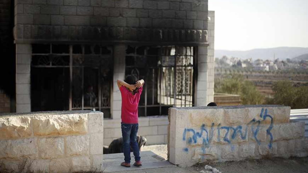 PALESTINIANS-ISRAEL/ARSON A Palestinian girl stands outside her torched house next to graffiti spray-painted on an outside wall of the home, in the West Bank village of Sinjil, near Ramallah November 14, 2013. Israeli settlers set fire to a Palestinian house on Thursday, leaving behind a message saying they were avenging the death of Eden Attias, an Israeli soldier killed by a Palestinian the previous day, residents said. The graffiti reads "Regards to Eden, Revenge!." REUTERS/Mohamad Torokman (WEST BANK - Tags: POLITICS CIVIL UNRES