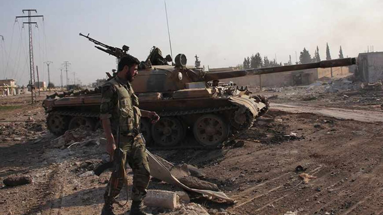 SYRIA-CRISIS/ALEPPO A soldier loyal to Syria's President Bashar al-Assad holds his weapon as he stands near a military vehicle in Tel Hasel, Aleppo province after capturing it from rebels November 15, 2013. State television aired a report on Friday it said was filmed in the centre of the town of Tel Hasel, 10 km (6 miles) south-east of Aleppo. The town is the third on the road to Aleppo to be taken by Assad's forces this month after the capture of Safira, close to a former chemical weapons site, and Tel Arn. REUTERS/George Our
