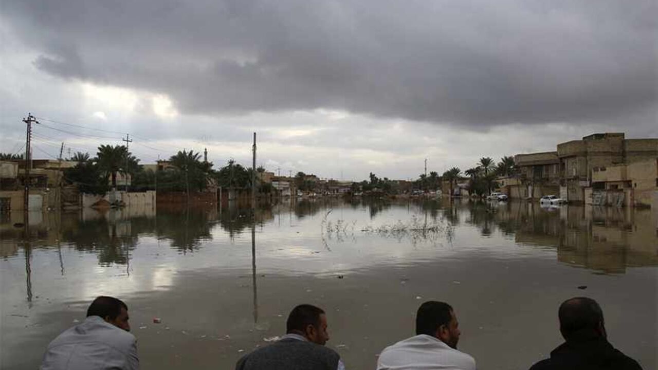IRAQ/ People sit on high ground watching their submerged houses after heavy rain fell in Najaf, 160 km (100 miles) south of Baghdad, November 20, 2013. REUTERS/ Ahmad Mousa (IRAQ - Tags: ENVIRONMENT DISASTER) - RTX15LZF
