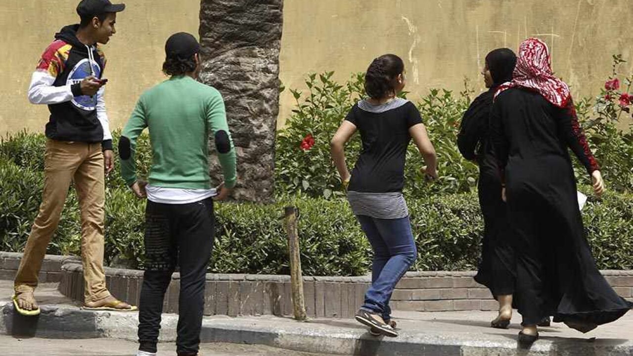 EGYPT/ Youth try to harass women on a street in Cairo April 8, 2013. Egypt's National Council for Women (NCW) has proposed a new law against sexual harassment containing a minimum sentence of one-year imprisonment for first-time offenders, local media reported. Picture taken April 8, 2013. REUTERS/Amr Abdallah Dalsh (EGYPT - Tags: POLITICS) - RTXYEPA