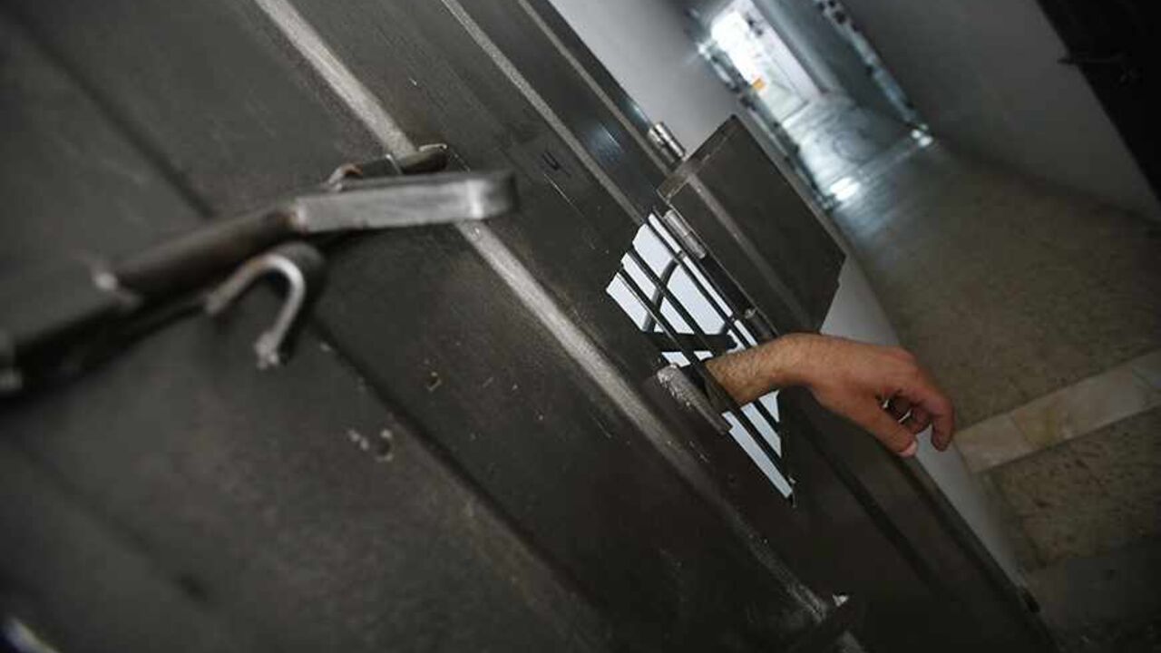 PALESTINIANS-HAMAS/SPIES The hand of an alleged Palestinian collaborator hangs out of his cell as he speaks with a security guard inside a Hamas-run prison in Gaza City April 23, 2013. The Islamist Hamas government, which is pledged to Israel's destruction by force of arms, is lauding a recent campaign to root out informants in its midst, which it hopes will deprive Israel of a subtle but effective tool. Picture taken April 23, 2013. To match Feature PALESTINIANS-HAMAS/SPIES REUTERS/Suhaib Salem (GAZA - Tags: POLITICS) - RTXZEXX