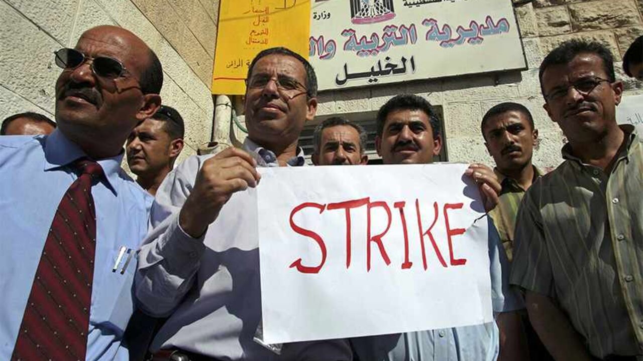 MIDEAST STRIKE Public school teachers demonstrate in front of a ministry of education office on the first day of the new academic year in the West Bank city of Hebron September 2, 2006. Tens of thousands of Palestinian government employees went on strike in the West Bank and Gaza on Saturday in protest against unpaid salaries and the perceived failings of the Hamas-led government. REUTERS/Nayef Hashlamoun (WEST BANK) - RTR1GWVF