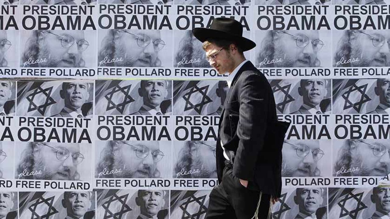 ISRAEL-PALESTINIANS/OBAMA An ultra-Orthodox Jewish man walks past posters calling for U.S. President Barack Obama to free Jonathan Pollard from a U.S. prison, in Jerusalem March 20, 2013. Obama arrives in Israel on Wednesday without any new peace initiative to offer disillusioned Palestinians and facing deep Israeli doubts over his pledge to prevent a nuclear-armed Iran. Pollard, a former U.S. Navy intelligence analyst, has been serving a life sentence in the United States since he was caught spying for Israel in the 1980s. REUTERS/