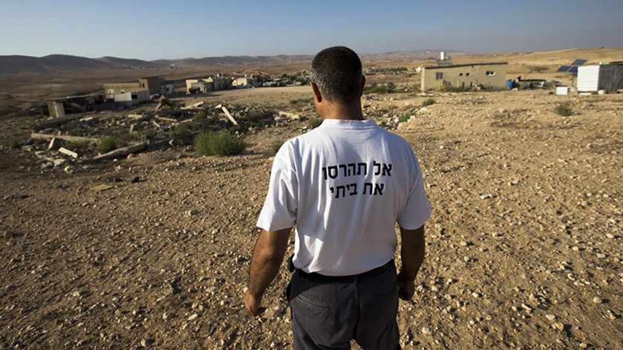 ISRAEL-BEDOUINS/EVICTION A Bedouin man, wearing a T-shirt reading which reads: "Don't destroy my home", stands in the village of Alsra, one of the dozens of ramshackle Bedouin Arab communities in the Negev desert which are not recognised by the Israeli state, in southern Israel August 18, 2013. For decades Arab Bedouins have eked out a meagre existence in the Negev desert, largely under the Israeli government's radar, but now many will have to make way for new developments. Israel has already invested around $5.6 billion to build m