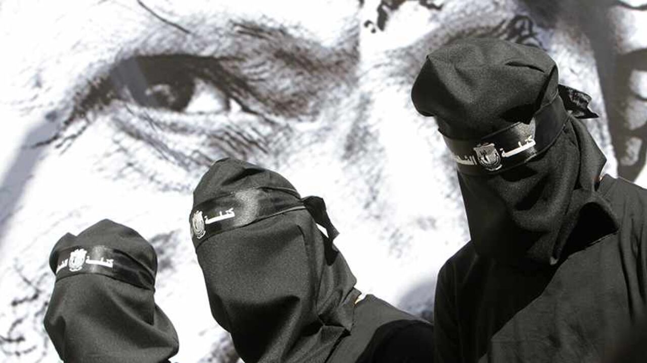 PALESTINIANS-ISRAEL/ Masked Palestinian Fatah supporters stand in front of a poster depicting late Palestinian leader Yasser Arafat during a rally marking the 9th anniversary of his death at al-Najah University campus in the West Bank city of Nablus November 10, 2013. REUTERS/Abed Omar Qusini (WEST BANK - Tags: POLITICS ANNIVERSARY) - RTX157QB
