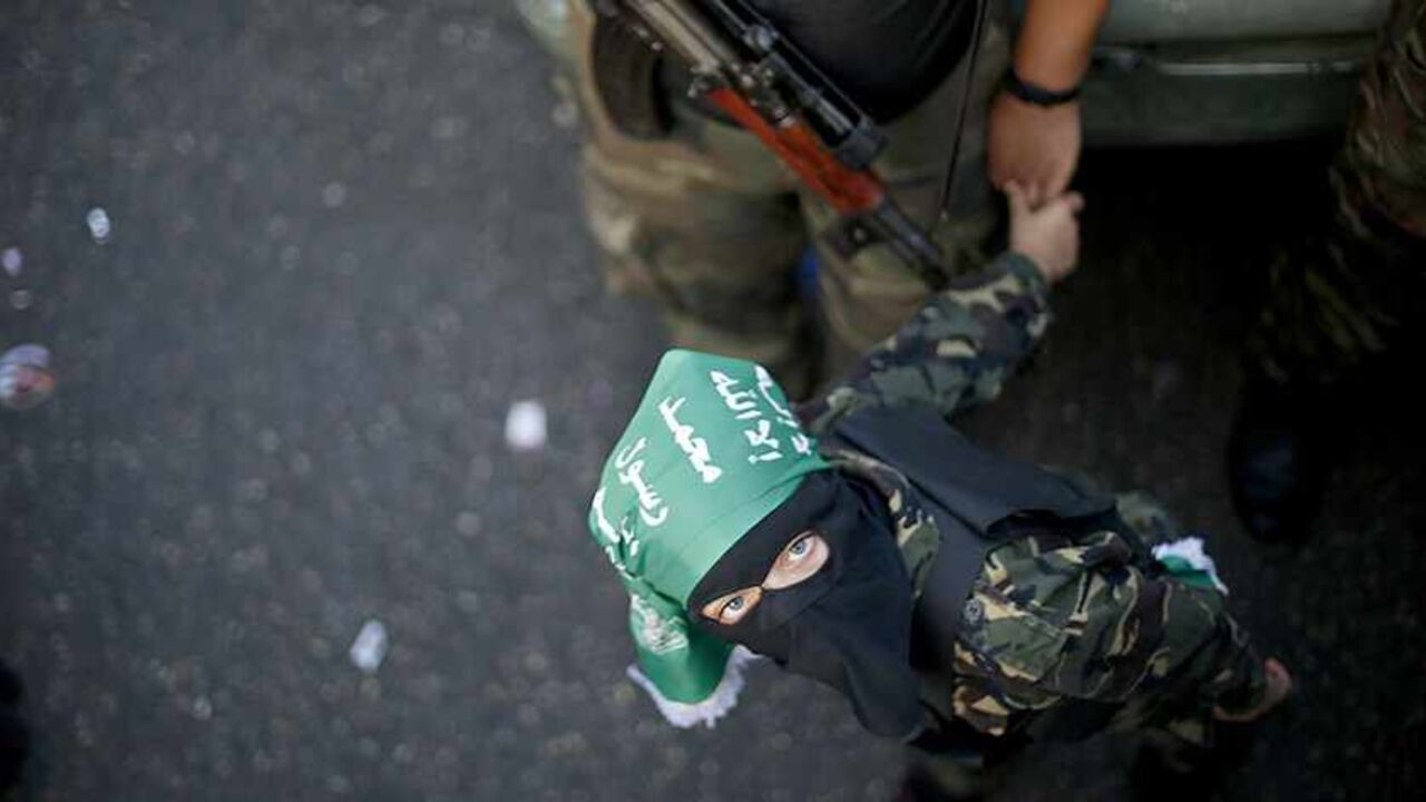 PALESTINIANS-GAZA/HAMAS A Palestinian boy and his militant father take part in a military parade marking the first anniversary of the eight-day conflict with Israel, in Gaza City November 14, 2013. The Palestinian Islamist movement Hamas looked to project an image of strength in Gaza on Thursday, organising one of its largest ever military parades to mark the first anniversary of an eight-day conflict with Israel. REUTERS/Suhaib Salem (GAZA - Tags: POLITICS CIVIL UNREST TPX IMAGES OF THE DAY) - RTX15DMK